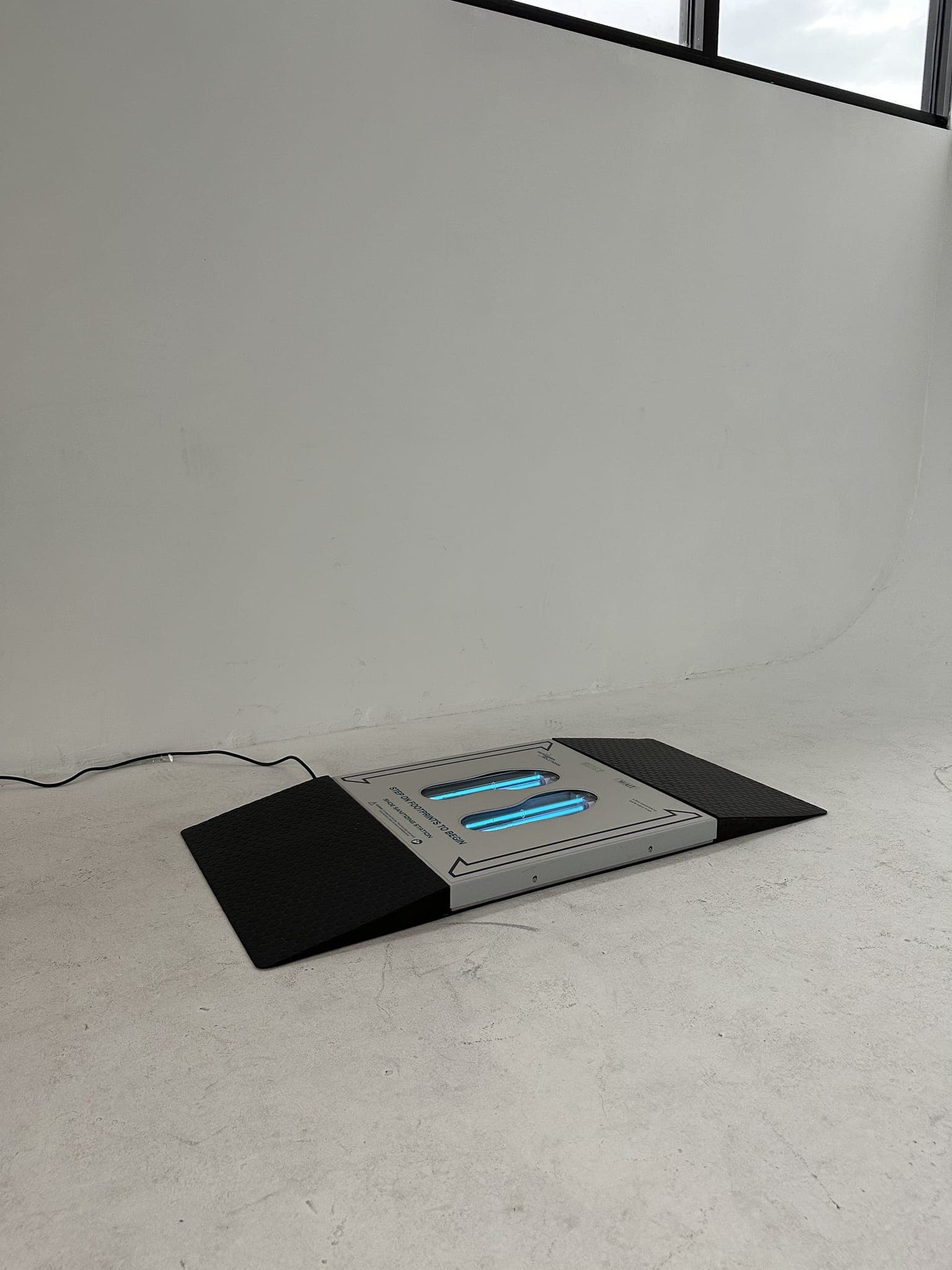 UVZone shoe sanitizing station with a black ramp at each end on a concrete floor