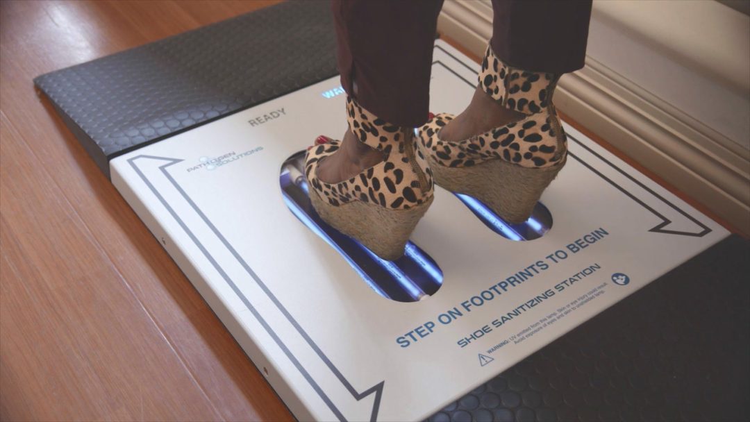 A woman wearing high heels sanitizing her footwear using the PathO₃Gen Solutions' UVZone® Shoe Sanitizer for improved hygiene.